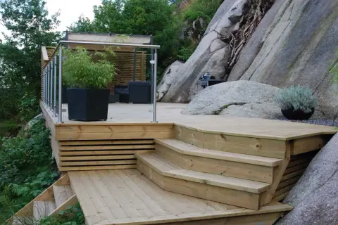 En nybyggd trappa på berg ger tillgång till en altan med sittgrupp och grillplats.