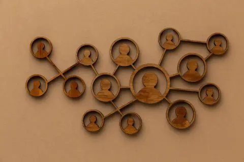 Drewniane figurki ludzi połączone ze sobą, symbolizujące podejście systemowe w psychologii i relacje międzyludzkie.