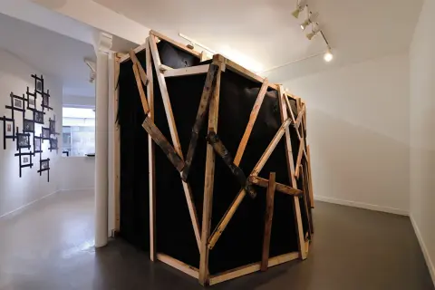 Instalacja artystyczna z czarnym materiałem i drewnianą konstrukcją, nawiązująca do prac Miroslava Tichego.