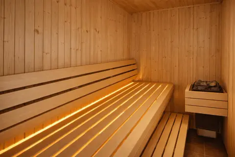 En varm och inbjudande bastu med träbänkar och diskret belysning. Perfekt bastu inspiration för avkoppling.
