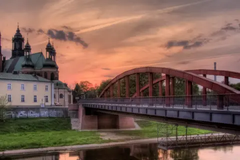 Zachód słońca nad Wartą w Poznaniu, z katedrą i mostem Jordana w tle.