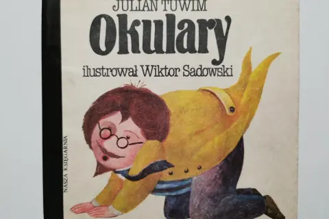 Okładka książki Juliana Tuwima "Okulary" z ilustracją Wiktora Sadowskiego. Dziecko w okularach na czworakach.