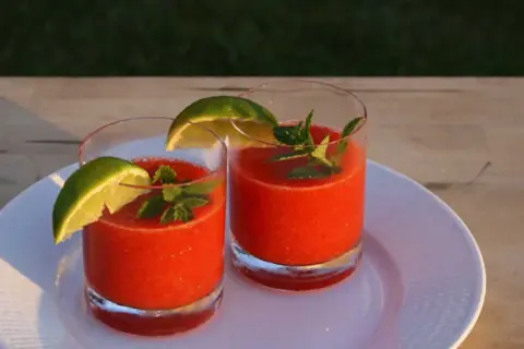 Två glas med en uppfriskande strawberry daiquiri, garnerade med lime och mynta. Perfekt för en solig sommardag.