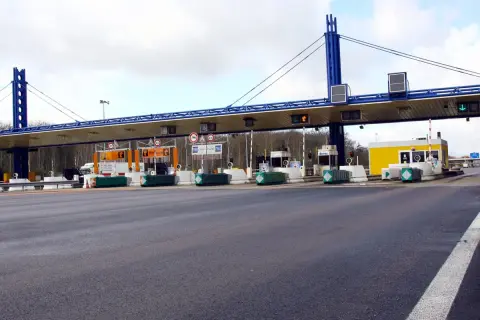 Péage d'autoroute avec plusieurs voies de passage. Une voiture attend à une borne de péage.