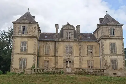 Vaste manoir abandonné en Bretagne, aux façades décrépites et aux volets clos, témoignant d'une histoire oubliée.