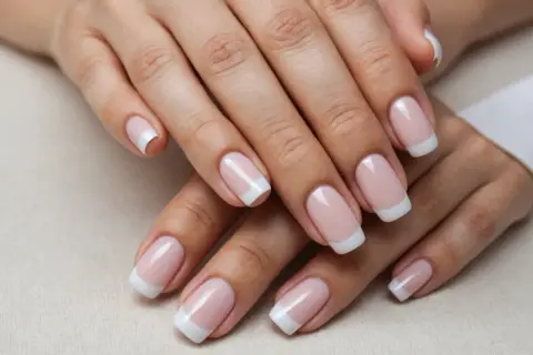 Mains soyeuses aux ongles mat, manucure française classique et impeccable.