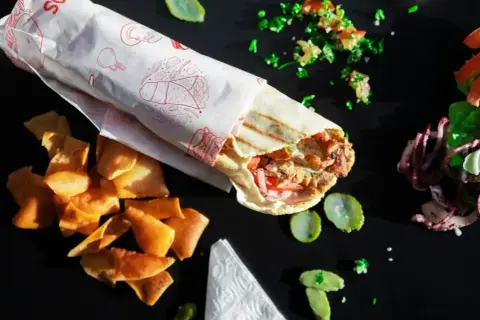 Pyszny kebab w tortilli z chrupiącymi chipsami i świeżymi dodatkami, gotowy do zjedzenia.
