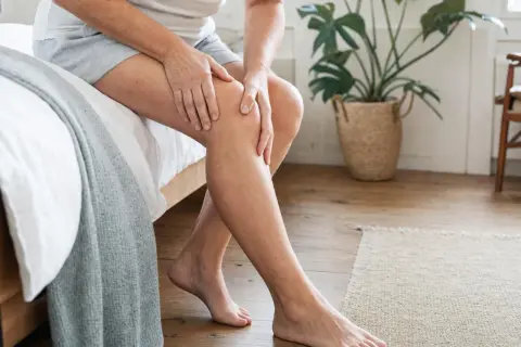 Donna si tocca il ginocchio, forse per un problema al liquido sinoviale.