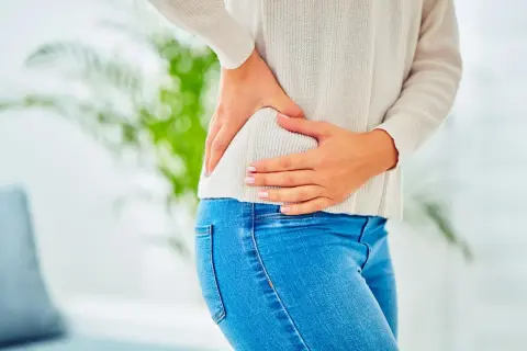 Témoignage : une femme se tient la hanche, souffrant de douleurs. Une infiltration de la hanche pourrait soulager.