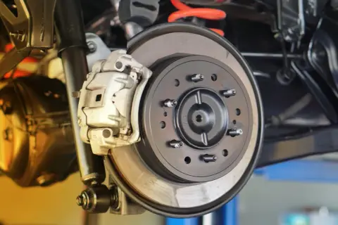 Nahaufnahme einer Autobremsanlage. Ein Mechaniker prüft, wann bremsscheiben wechseln, um die Sicherheit zu gewährleisten.