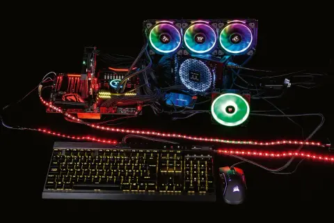 Ein PC-Aufbau mit leuchtenden Lüftern und RGB-Streifen, die zeigen, was ist RGB-Beleuchtung. Tastatur und Maus leuchten ebenfalls.