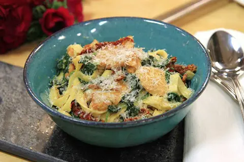 En härlig kycklingpasta med soltorkade tomater och spenat, perfekt för ett snabbt och gott kycklingpasta recept. Serveras i en vacker blå skål.