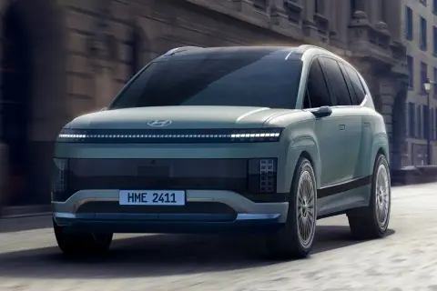 Przyszłościowy Hyundai Ioniq 9 w kolorze miętowym przemierza miejskie ulice, prezentując swój unikalny design i innowacyjne oświetlenie.