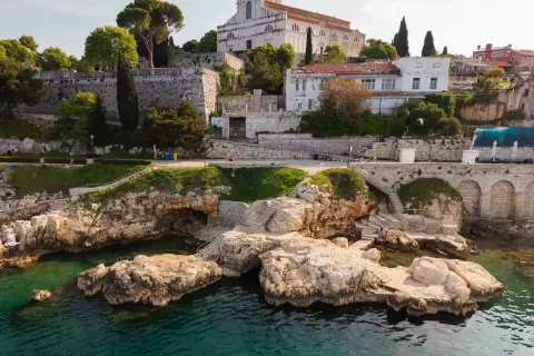 Felsige Küste mit kristallklarem Wasser und einer Kirche auf dem Hügel. Entdecke Rovinj Geheimtipps abseits der Touristenpfade.