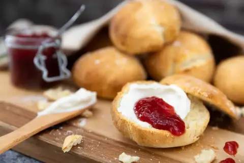 Lyxiga scones med grädde och sylt på en träbricka. En härlig fika!
