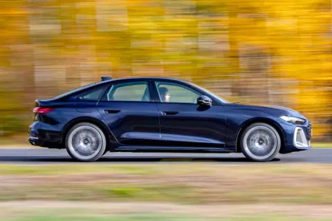 Ciemnoniebieskie Audi A4 B10 w ruchu, z rozmytym tłem jesiennych drzew.