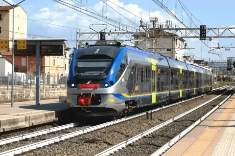 Nowoczesny pociąg wjeżdża na stację, przypominając miejski transport, jak neapol metro.