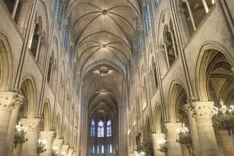 Das Innere der Notre Dame erstreckt sich mit seinen gotischen Bögen und Gewölben in die Höhe. Buntglasfenster erhellen den Raum.