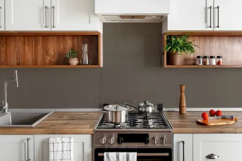 Cocina moderna con pared mitad azulejo gris y mitad estante de madera. Ollas en la estufa, grifo y plantas decorativas.