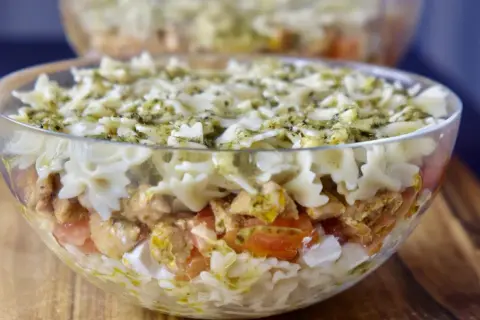Pyszna sałatka z kurczakiem i makaronem farfalle, polana sosem pesto. Idealna na letnie przyjęcie.