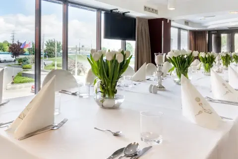 Elegancko nakryty stół z białymi tulipanami, idealny na uroczystość. Zastanawiasz się, ile trwa komunia w restauracji? To zależy od wielu czynników, ale zazwyczaj trwa kilka godzin.