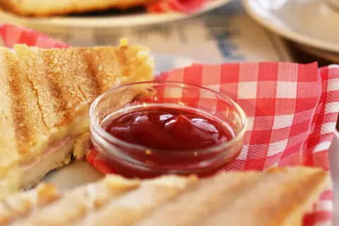 Un sándwich a la parrilla con una pequeña taza de ketchup. ¿El ketchup es dulce o salado?