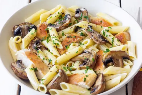 Penne z kurczakiem i pieczarkami, posypane natką pietruszki i pieprzem. Pyszne danie, które z pewnością zadowoli każdego miłośnika makaronu z kurczakiem.