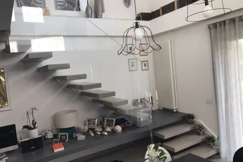 Scala interna moderna con gradini a sbalzo e parapetto in vetro. Un modo elegante per come abbellire una scala interna con decorazioni e piante.