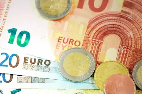Euro banknoty o nominałach 10 i 20 oraz monety. Obrazek symbolizuje wskaźnik ogólnego zadłużenia.