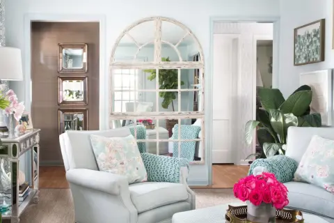 Charming mirror wall ideas: a large arched window mirror and stacked square mirrors create depth and light in this elegant living room.