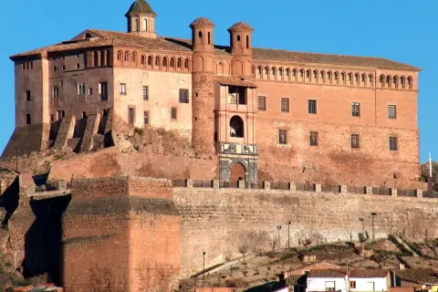 Imponente castillo Zaragoza, con sus torres y cúpulas, se alza sobre una colina rocosa, vigilando el paisaje.