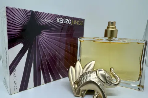 Złoty słoń strzeże flakonu Kenzo Jungle 100ml z fioletowym, liściastym wzorem na opakowaniu.