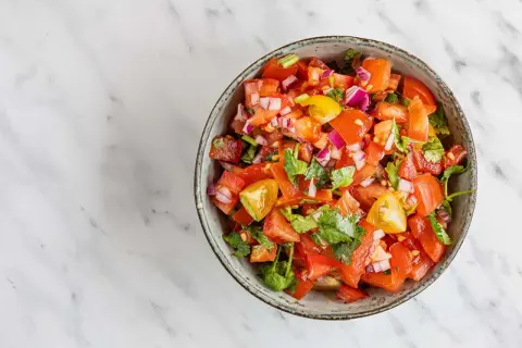 En skål med färsk pico de gallo, full av tärnad tomat, rödlök och koriander. Perfekt till tacosen!