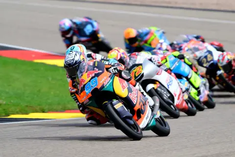 Pilotos de Moto3 compiten en una carrera, mostrando la potencia y velocidad de estas motos. El número 99 destaca en primer plano.