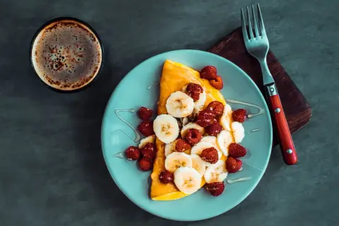 Słodki omlet z bananem i malinami, polany miodem. Idealny przepis na omlet na słodko na śniadanie.