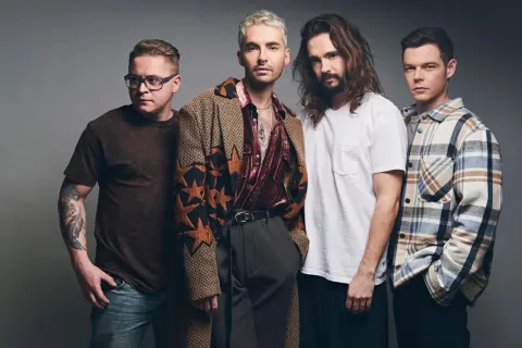 Tokio Hotel Polska: czterech mężczyzn w stylowych strojach pozuje do zdjęcia. Jeden z nich ma tatuaż na ramieniu.