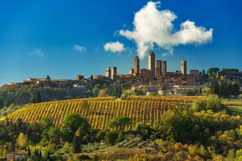 San Gimignano, con le sue torri medievali, domina un paesaggio collinare autunnale, con vigneti che promettono la vernaccia di San Gimignano DOCG.