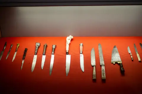 Ausstellung im Klingenmuseum Solingen: Eine Reihe historischer Messer mit kunstvollen Griffen auf rotem Samt.