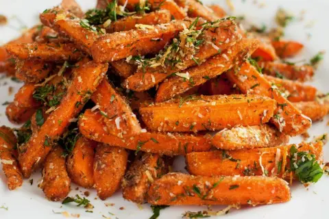 Chrupiące frytki z marchewki, posypane ziołami i parmezanem, wyglądają apetycznie.
