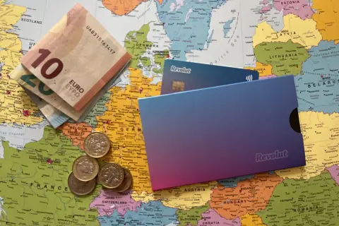 Euro banknoty, monety i karty Revolut leżą na mapie Europy. Czy Revolut jest darmowy? Sprawdź, zanim wyruszysz w podróż!