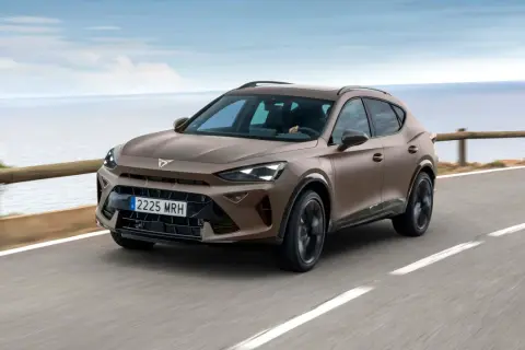 Brązowy Cupra Formentor na krętej drodze nad morzem. Sprawdź cupra formentor dane techniczne.