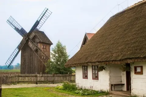 Drewniany wiatrak i biały domek z krytym strzechą dachem tworzą malowniczą zagrodę młynarską w Uniejowie.