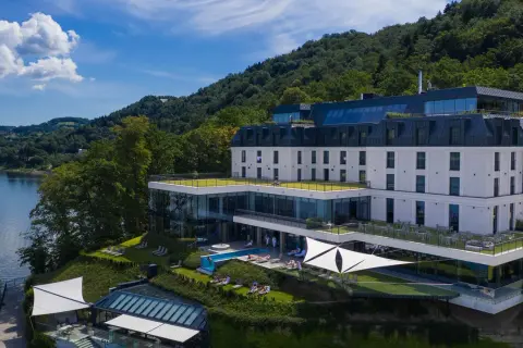 Nowoczesny hotel nad jeziorem Rożnowskim, z basenem i tarasami, otoczony zielenią.
