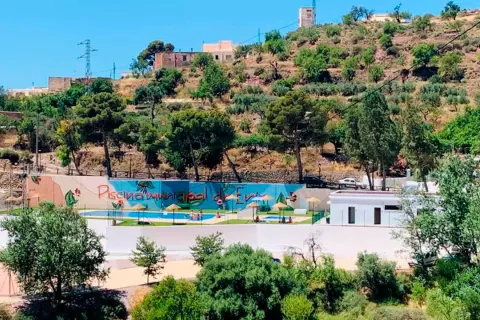 Piscina municipal en el oeste de Almería, rodeada de vegetación y colinas. Un oasis refrescante bajo el sol andaluz.
