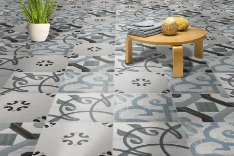 Un suelo hidráulico con un diseño de azulejos en tonos grises y azules, con un pequeño taburete de madera y una planta. ¡Perfecto para limpiar y lucir!