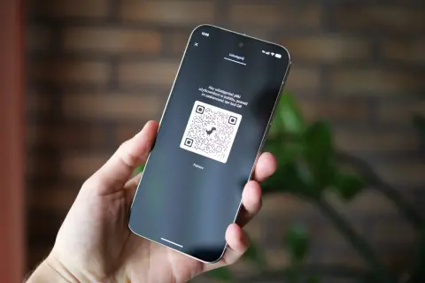 Dłoń trzyma smartfon z wyświetlonym kodem QR, który można zeskanować, aby udostępnić pliki.