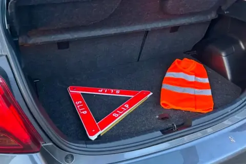 Triangle de signalisation et gilet de haute visibilité dans un coffre de voiture, prêts pour la signalisation dépassement chargement arrière.