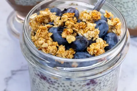 Szybki deser z chia i bananem: pudding chia z jagodami i granolą w słoiku.