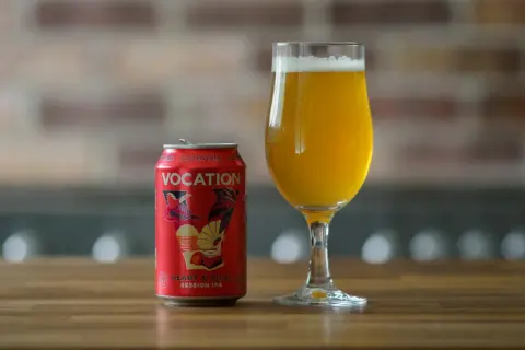 Czerwona puszka piwa Vocation Heart & Soul Session IPA z napisem "Gluten Free" obok szklanki z bursztynowym piwem. To piwo nie ma glutenu.