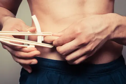Uomo con plicometro misura il grasso corporeo, un dettaglio per capire il significato di ectomorfo e la sua costituzione fisica.